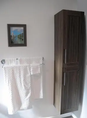 a bathroom with a wooden cabinet and white towels at Champagne Retreat in Upland