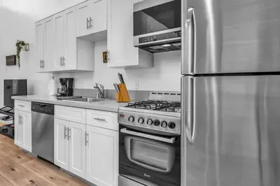 a kitchen with white cabinets and a stainless steel refrigerator at Stylish 1 Bedroom Loft in Hollywood Balcony Free Gated Parking In Unit Laundry in Los Angeles