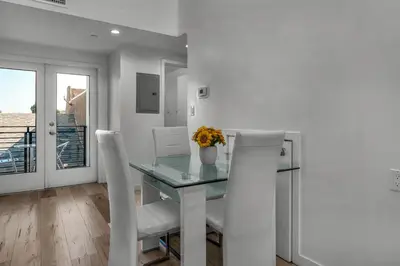 a dining room with a glass table and white chairs at Koreatown Hollywood Urban Oasis 1 Bedroom Loft with Private Parking and Balcony in Los Angeles