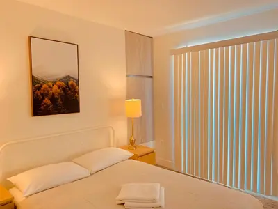 a white bedroom with a bed and a window at Western Romaine in Los Angeles