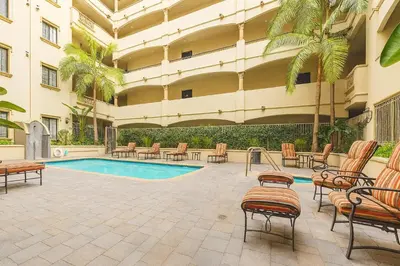 a courtyard with chairs and a swimming pool in a building at LA Koreatown Nest House - Modern, Free Parking, Pool and Sauna, No Cleaning Fee in Los Angeles