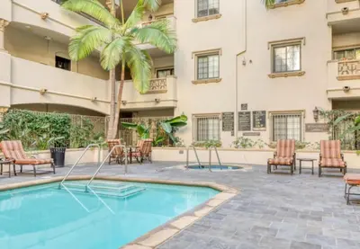 a courtyard with a pool and chairs and a palm tree at LA Koreatown Nest House - Modern, Free Parking, Pool and Sauna, No Cleaning Fee in Los Angeles