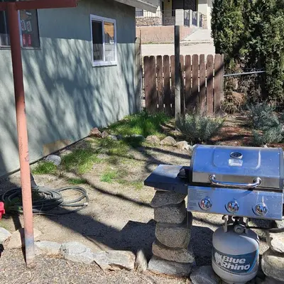 a blue grill sitting on a stone stand in a yard at Cozy Mountain Retreat in Frazier Park