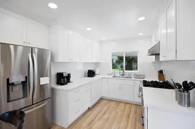 a kitchen with white cabinets and a stainless steel refrigerator at The Luxe Escape | Near LAX & West LA Hotspots in Los Angeles