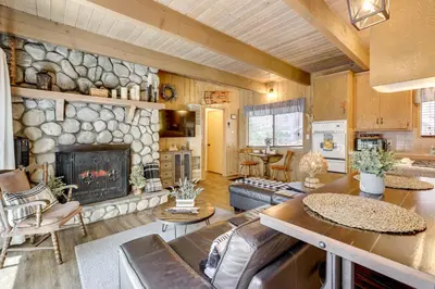 a living room with a stone fireplace in a house at 2 Mi to Lake Arrowhead Pet-Friendly Cabin in Lake Arrowhead