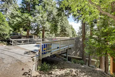 a wooden deck in the middle of a yard with trees at 2 Mi to Lake Arrowhead Pet-Friendly Cabin in Lake Arrowhead