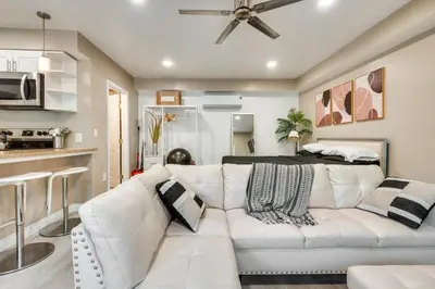 a living room with a white couch and a kitchen at 4 Mi to Hollywood Mid-Wilshire Couples Retreat in Los Angeles