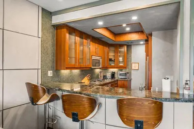 a kitchen with wooden cabinets and bar stools at Stylish Westwood Condo, Near UCLA & Century City in Los Angeles