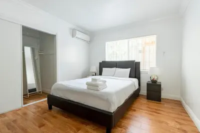a bedroom with a large bed with white walls and wood floors at Ideal 4BR2BA Home for Family Vacations in Alhambra