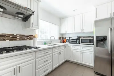 a kitchen with white cabinets and a stainless steel refrigerator at Ideal 4BR2BA Home for Family Vacations in Alhambra