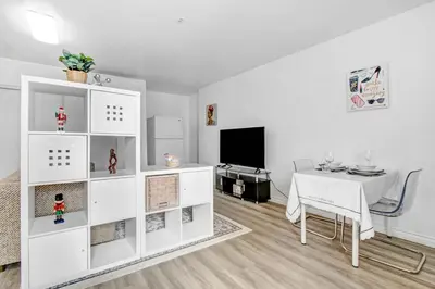 a white living room with a table and a tv at Cozy Guesthouse near Downtown Alhambra in Alhambra