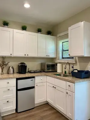 a white kitchen with white cabinets and a sink at Guest suite near La Cienega Park Beverly Hills next to LACMA La Brea Tar Pits Peterson Museum and Academy Awards Museum in Los Angeles