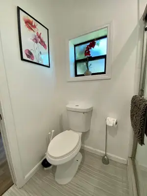 a white bathroom with a toilet and a window at Guest suite near La Cienega Park Beverly Hills next to LACMA La Brea Tar Pits Peterson Museum and Academy Awards Museum in Los Angeles