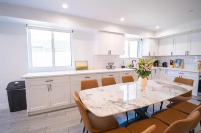 a kitchen with white cabinets and a table with chairs at Stylish Private Ensuite Room near USC in Los Angeles