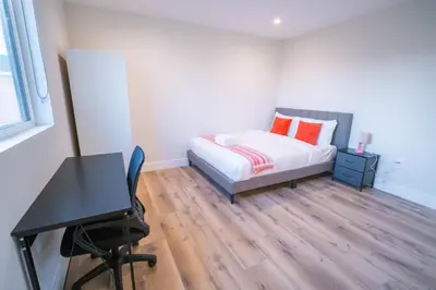 a bedroom with a bed with orange pillows and a desk at Modern Private Ensuite Room near USC in Los Angeles
