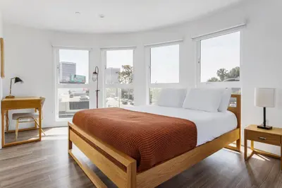 a bedroom with a bed with white sheets and windows at Blueground Sawtelle rooftop nr Culver City Park LAX-1373 in Los Angeles