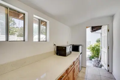 a kitchen with a microwave on a counter with windows at 3 Mi to Beaches Low-Key San Pedro Rental! in San Pedro