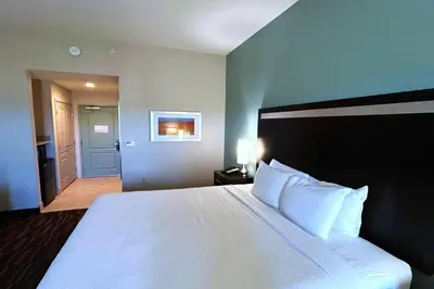 a bedroom with a large white bed and a hallway at Wyndham Garden Lancaster CA in Lancaster