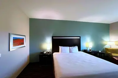 a hotel room with a large bed and a chair at Wyndham Garden Lancaster CA in Lancaster