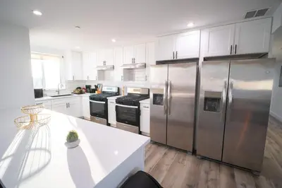 a kitchen with stainless steel appliances and white cabinets at The Command Suite Urban Comfort Near USC in Los Angeles