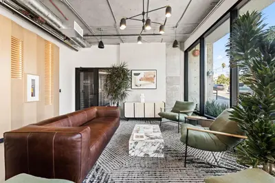 a living room with a brown leather couch and chairs at Chic Studio, Walk to Downtown With Skyline Views in Los Angeles