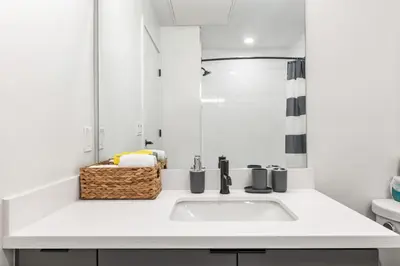 a white bathroom with a sink and a mirror at Chic Studio, Walk to Downtown With Skyline Views in Los Angeles