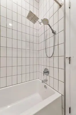 a shower in a white tiled bathroom with a tub at Arts District Stay, Walk to Little Tokyo with Parking in Los Angeles