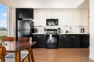 a kitchen with black and white cabinets and a table at 2BD 2BA Stylish Arts District Retreat, Walk to Little Tokyo in Los Angeles