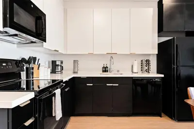 a kitchen with white cabinets and black appliances at Arts District Condo, Walk to Little Tokyo Plaza in Los Angeles