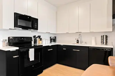 a kitchen with black appliances and white cabinets at Designer Stay in Arts District, Walk to Little Tokyo in Los Angeles