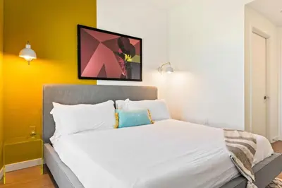 a bedroom with a large white bed with yellow walls at Designer Stay in Arts District, Walk to Little Tokyo in Los Angeles