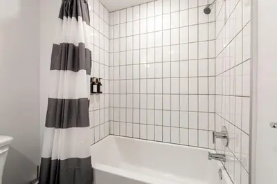 a bathroom with a tub and a shower curtain at Chic and Cozy Home, Walk to Little Tokyo with Parking in Los Angeles