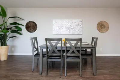a dining room table with four chairs and a plant at Modern Hollywood Apt Rooftop Pool & Skyline Views in Los Angeles