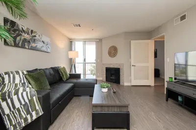 a living room with a black couch and a tv at Stylish 2BR Apt with Rooftop Pool & Hollywood Views in Los Angeles