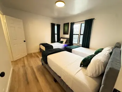 a room with three beds and a door with windows at Modern Duplex with 6 beds and Sofa bed in Miracle Mile Longwood in Los Angeles