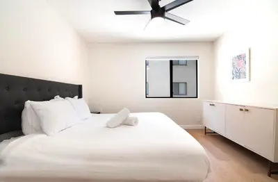 a bedroom with a large white bed with a ceiling fan at Stylish 1BR Near Universal Studios with Parking in Los Angeles