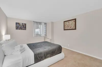 a white bedroom with a bed and a window at Sunset Boulevard Apartments in Los Angeles