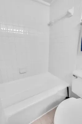 a white bathroom with a toilet and a bath tub at Sunset Boulevard Apartments in Los Angeles