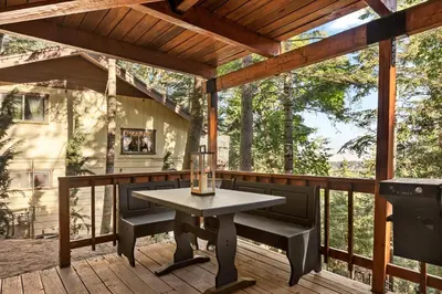 a patio with a table and chairs on a deck at Cute Romantic Cabin With Hot Tub 5 Min from Lake in Crestline
