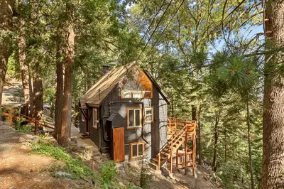 a small house in the middle of the woods at Cute Romantic Cabin With Hot Tub 5 Min from Lake in Crestline