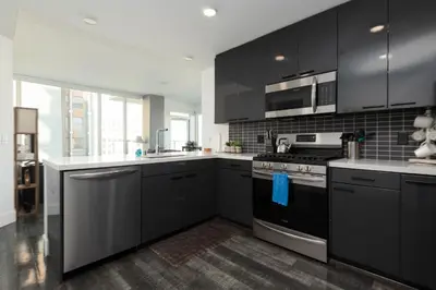 a kitchen with black cabinets and stainless steel appliances at Stunning 3BR High Rise Pool, Spa & Rooftop Views in Los Angeles