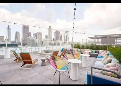 a rooftop patio with chairs and tables and a city skyline at Stunning 3BR High Rise Pool, Spa & Rooftop Views in Los Angeles