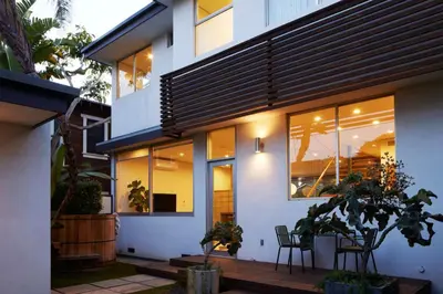 a house with white walls and windows and a wooden deck at Architectural Walk Street Home Venice Elegance in Los Angeles