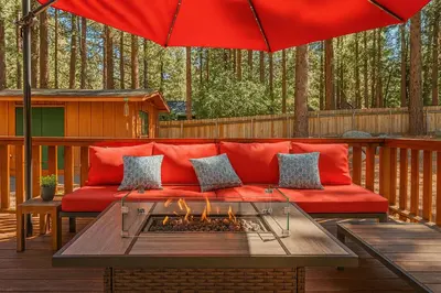 a red couch on a deck with a fire pit at Cozy Cabin with Large Backyard Near Lake, Village and Snow Summit in Big Bear Lake