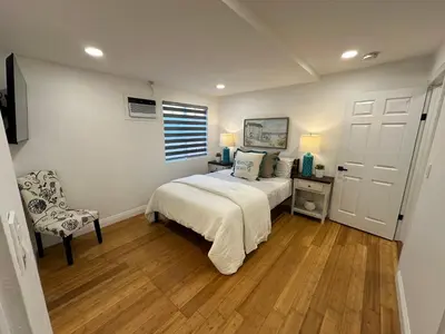 a bedroom with a bed and a chair and a window at Coastal Calm Casita in Long Beach