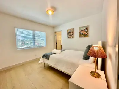 a bedroom with a bed with a lamp and a window at Modern and Charming Luxe Home in Los Angeles in Altadena
