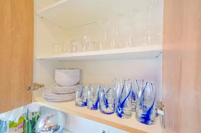 a shelf filled with clear glass vases and plates at H- Fab Family 5BD 4,5BA NoHo Escape Near Universal with Games, Deck, Parking in North Hollywood