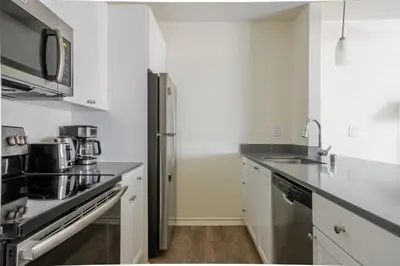 a kitchen with white cabinets and a stainless steel refrigerator at Blueground Pasadena pool nr Pasadena Park LAX-1391 in Los Angeles