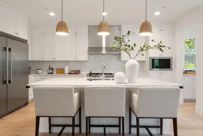 a kitchen with a large white island with chairs at 4mil WestLA Lux Manor Santa Monica and Beverly Hills in Los Angeles