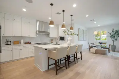 a kitchen with white cabinets and a kitchen island with chairs at 4mil WestLA Lux Manor Santa Monica and Beverly Hills in Los Angeles